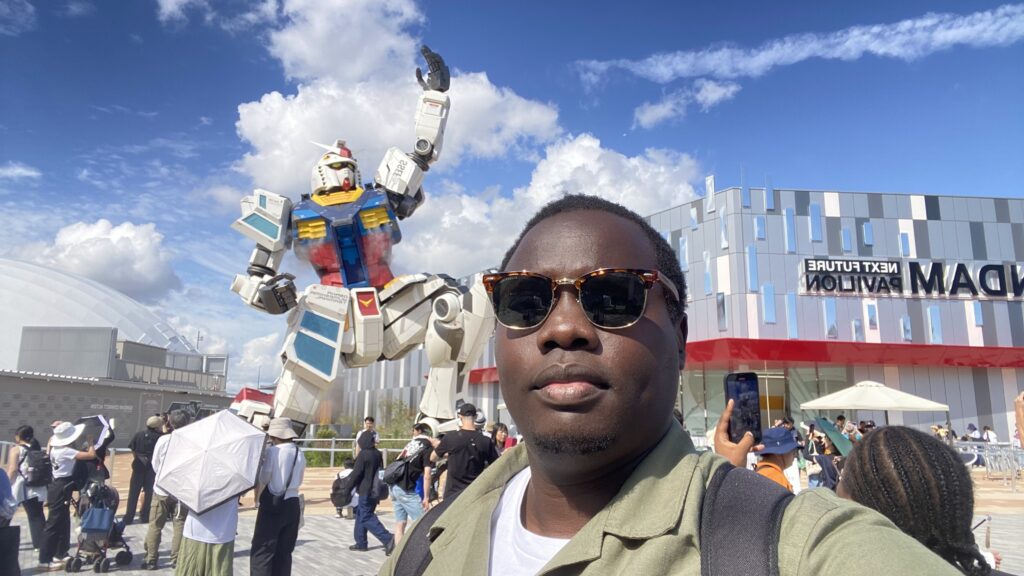 Ruyonga with Gundam San in the background in front of the Next Future Pavillion.  The future looks very different; we shall co-exist with machines and being able to do more together.